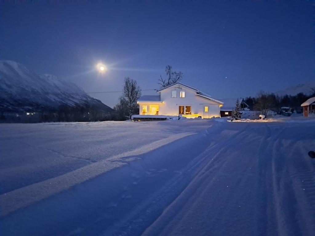 a house on a snowy road with the moon in the sky at Mountainside Lodge - Breivikeidet in Tromsø