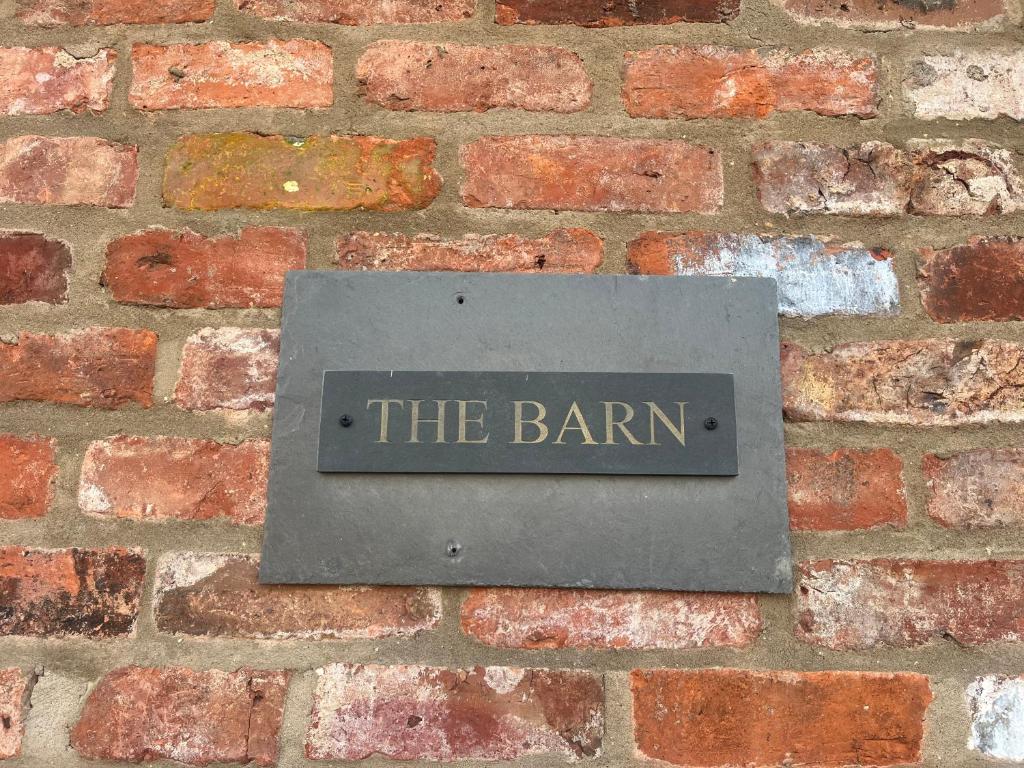 um sinal numa parede de tijolos que lê o celeiro em The Barn em Haxby