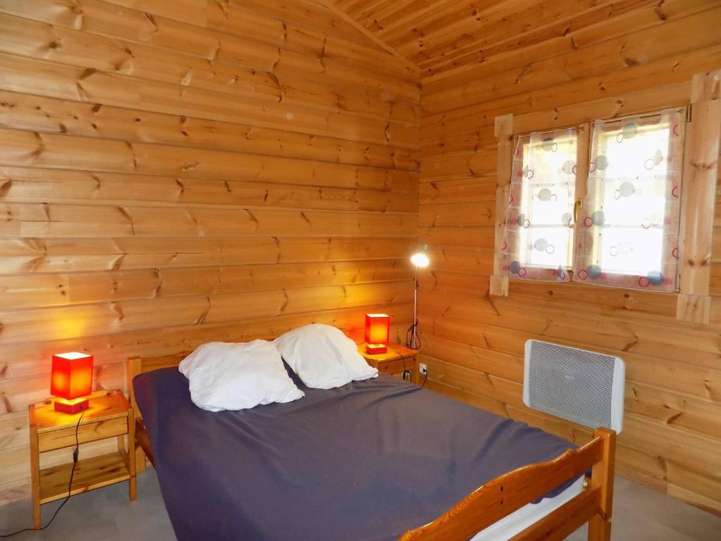 a bedroom with a bed in a log cabin at Les Mathes La Palmyre - MAISON CABANE des TRAPPEURS - PROCHE COMMERCES in Les Mathes