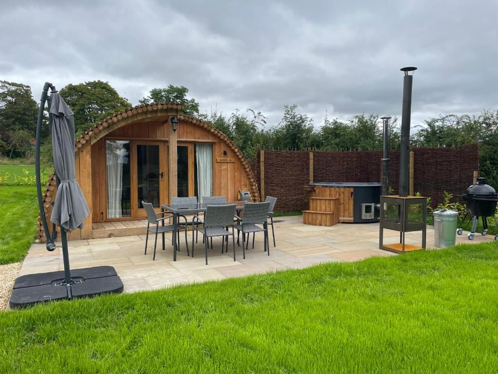 a patio with a table and chairs and an umbrella at Wimbish Hall Cabins in Wimbish