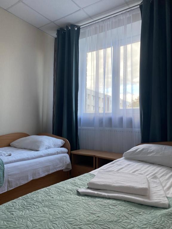 a bedroom with two beds and a window with blue curtains at Telšių Hotel in Telšiai