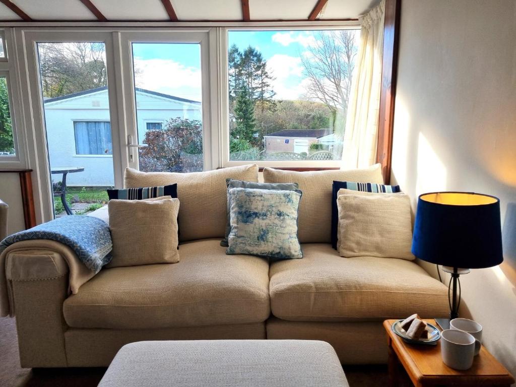 um sofá numa sala de estar com duas janelas em 2 bed property in Galmpton BX008 em Galmpton-on-the-Dart