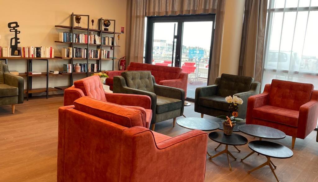 ein Wohnzimmer mit Sofas, Stühlen und einem Tisch in der Unterkunft Zenao Appart'hôtels Boulogne-sur-Mer - La Rose des Vents in Boulogne-sur-Mer