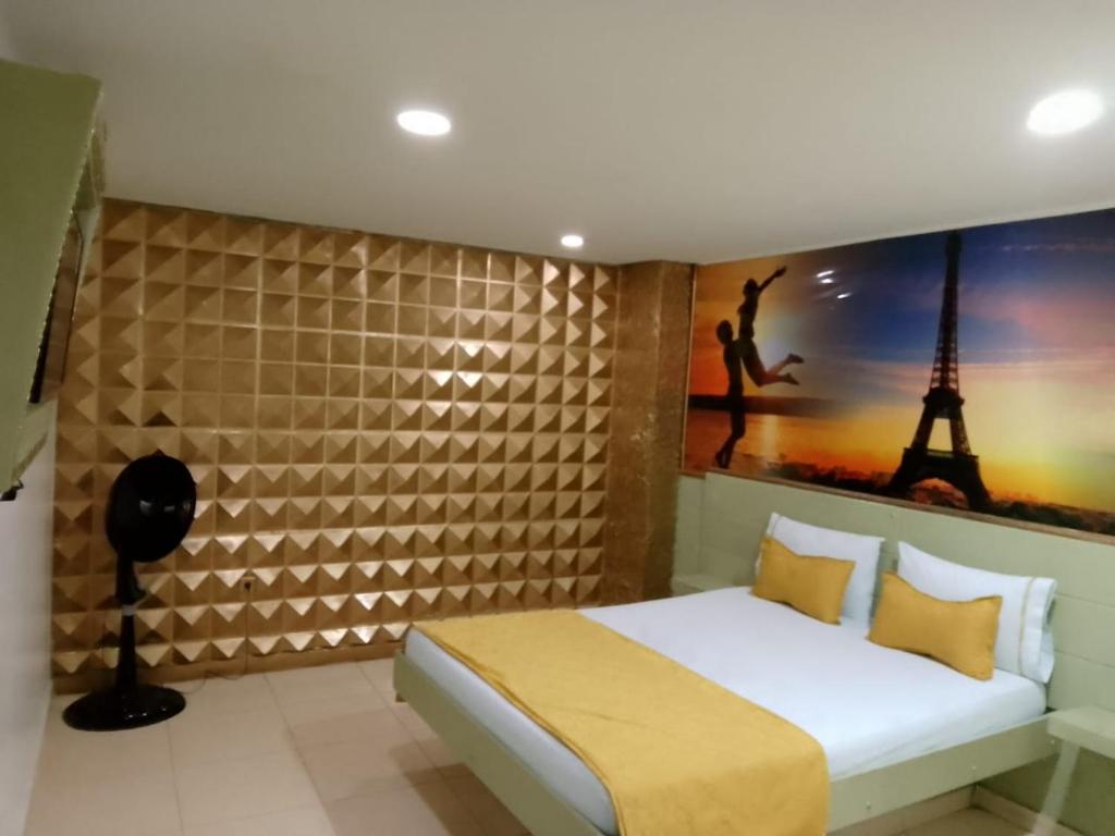 een slaapkamer met een bed en een schilderij van de eiffeltoren bij Hotel el playon in Medellín