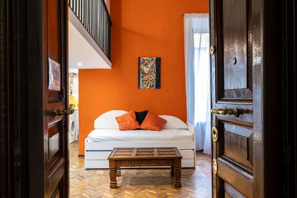 ein Schlafzimmer mit einem Bett mit einer orangefarbenen Wand in der Unterkunft La Cupola Apartment in Rom