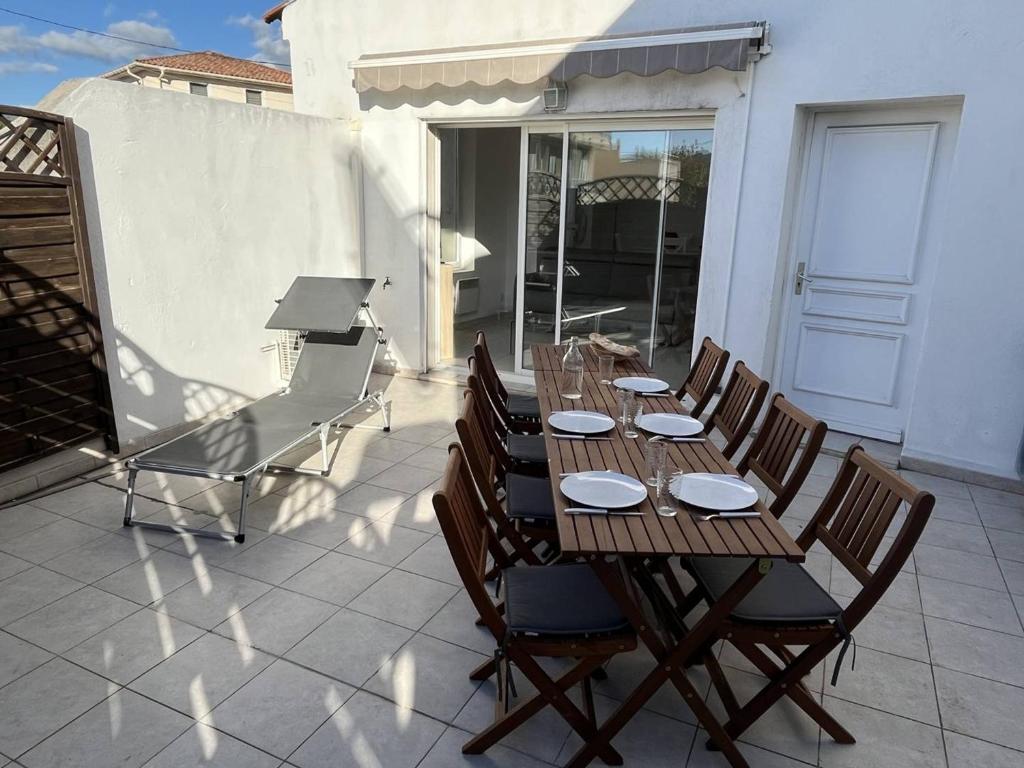 une table et des chaises en bois sur une terrasse dans l'établissement Appartement T3 lumineux avec grande terrasse, clim, parking gratuit et Wi-Fi - 5 personnes - FR-1-770-6, à La Ciotat
