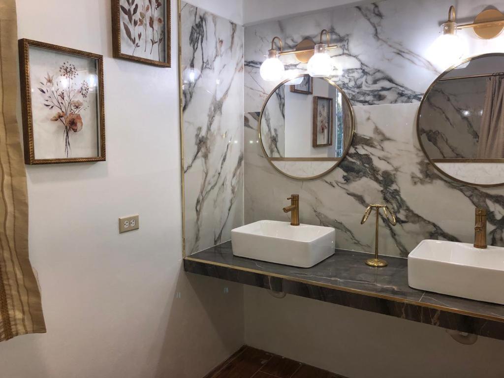 a bathroom with two sinks and two mirrors at Banyan Rose Room 4 in Orange Walk