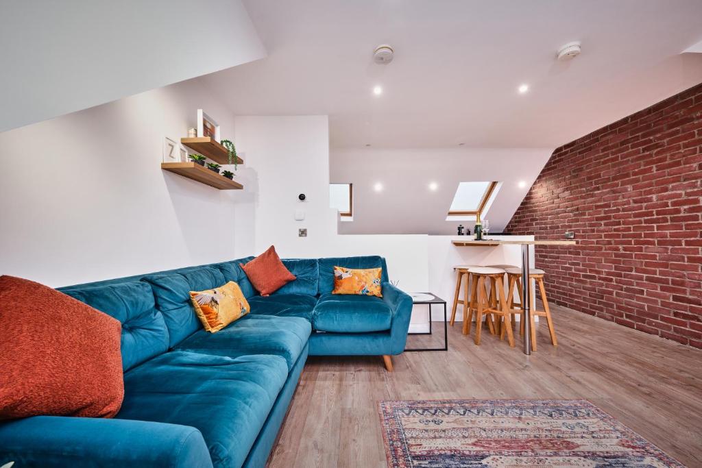 a living room with a blue couch and a brick wall at Portstewart Central Loft Apartment in Portstewart