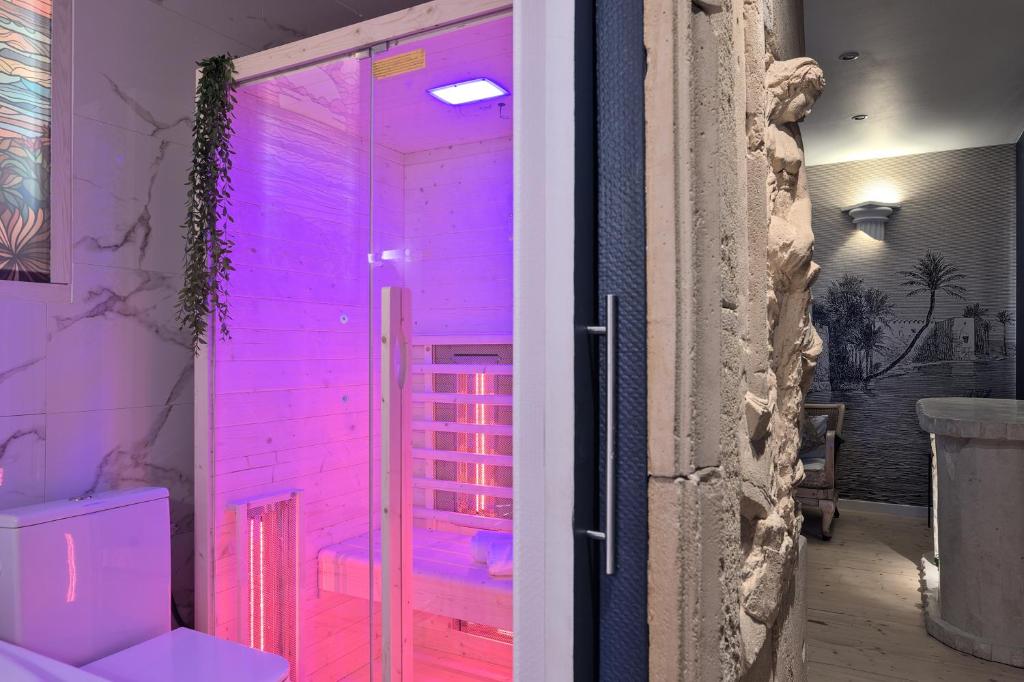 - une salle de bains avec des lumières roses sur la porte dans l'établissement UnSejourAMetz - Le mille et une nuits, à Metz