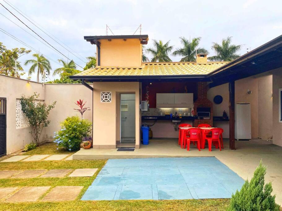 a house with a patio with red chairs and a kitchen at Aconchegante casa perto da praia in Fundão