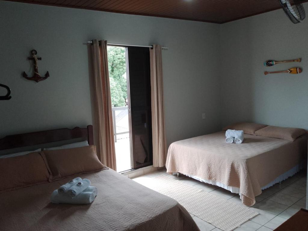 um quarto com 2 camas e uma grande janela em Pousada Amanhecer do Itaguá em Ubatuba