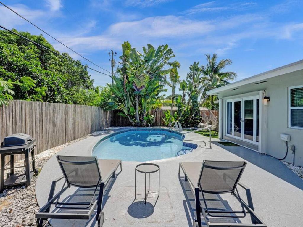 a patio with chairs and a swimming pool at Poolside Paradise Spacious 3BR Haven near Pompano Beach in Pompano Beach