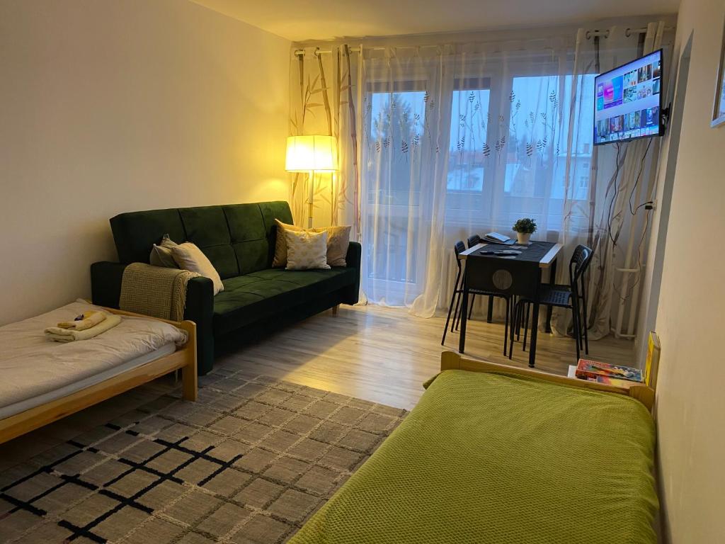 a living room with a green couch and a table at Apartament Piechoty Tanie spanie in Elblag