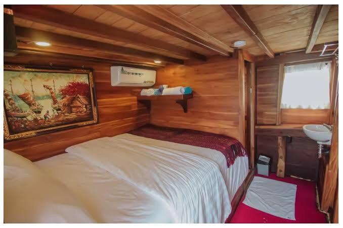 a bedroom with a bed and a sink in a cabin at Phinisi Floresta Komodo in Labuan Bajo