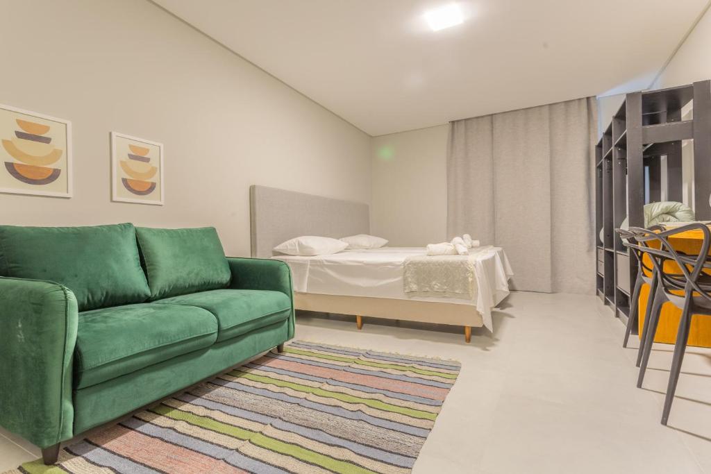 uma sala de estar com um sofá verde e uma cama em Studio Itapema a 230m da Passarela na Barra WV4437 em Balneário Camboriú