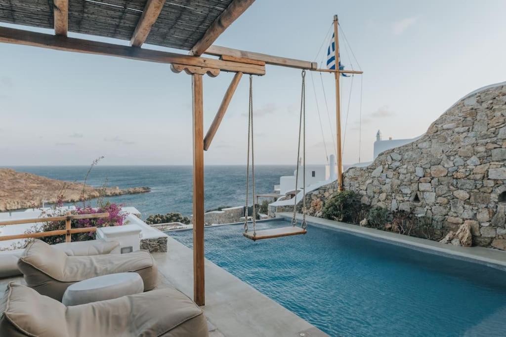 a swimming pool with a swing and the ocean at Private Cliffside Villa "150 meters from the beach" in Mikonos