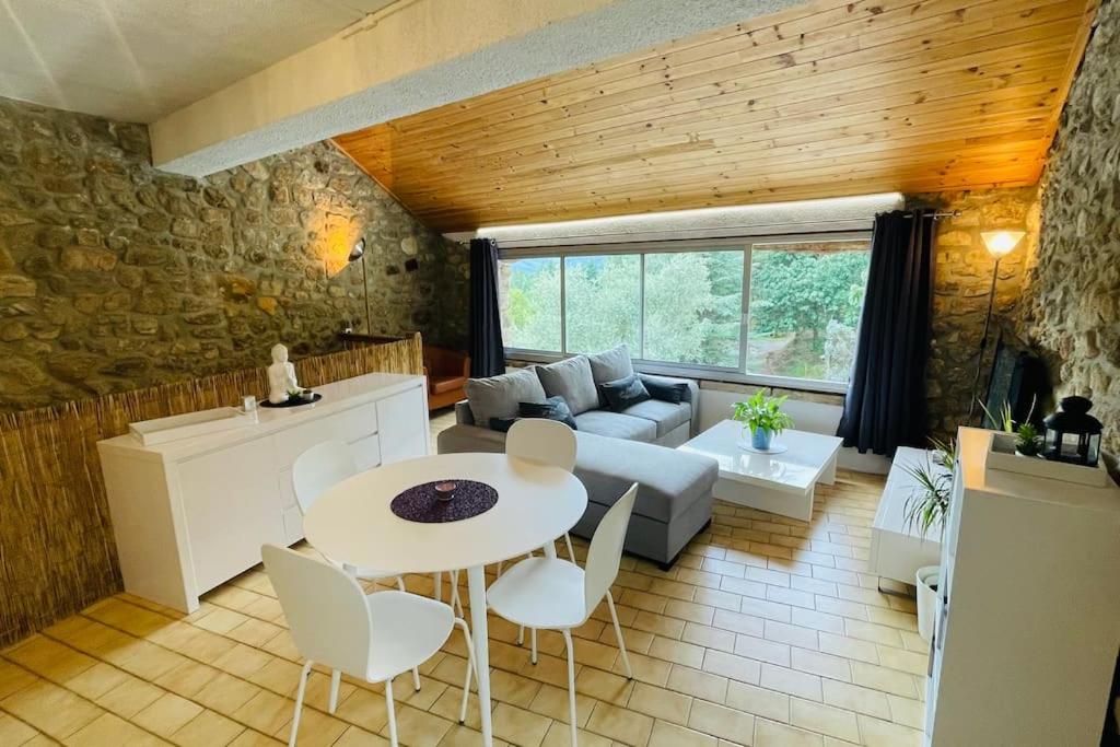 una sala de estar con un sofá y una mesa en Gîte des 3 vallées - Le soleil des Cévennes, en Saint-Jean-du-Gard