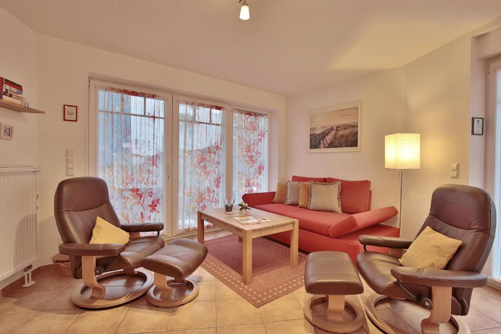 sala de estar con sofá rojo y sillas en Strandvilla Strandvilla Appartement 7, en Scharbeutz