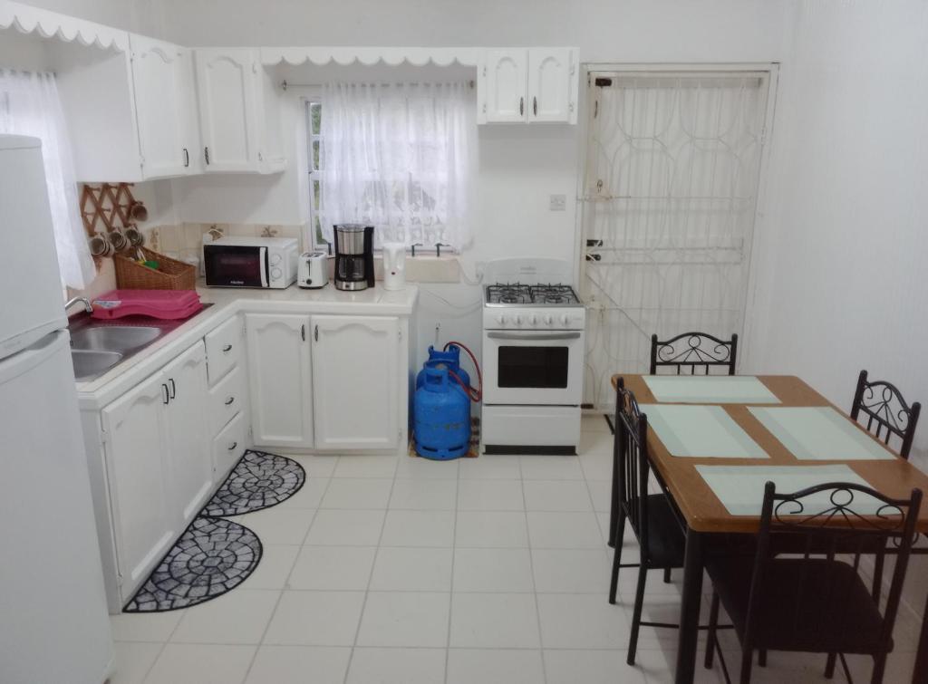 a kitchen with white appliances and a table with chairs at Chez Emmanuel in Gros Islet