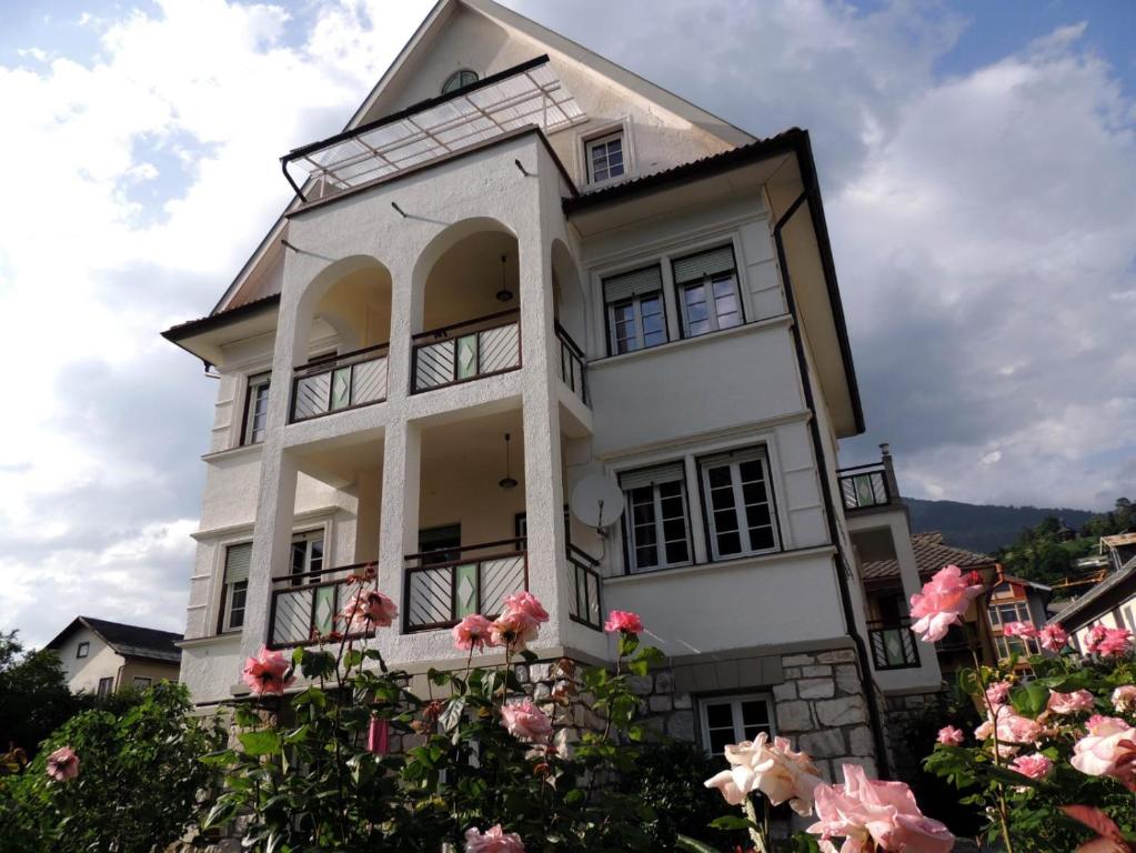 ein weißes Haus mit rosa Rosen davor in der Unterkunft Villa Werndl in Millstatt