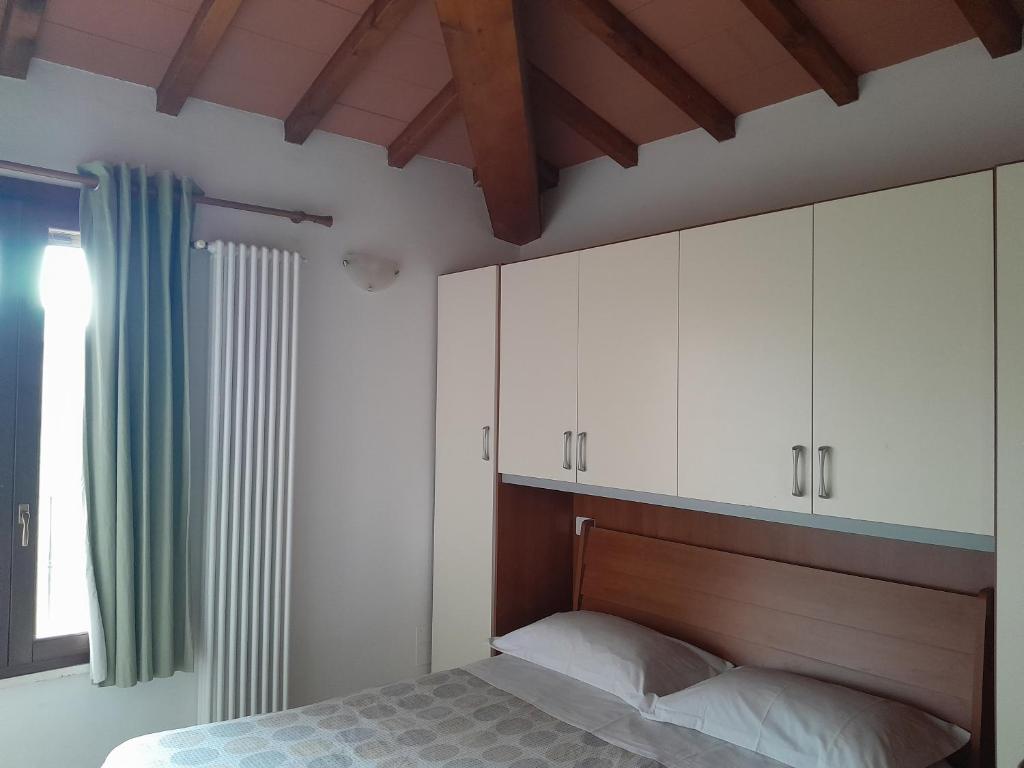 um quarto com uma cama, armários brancos e uma janela. em Finestra Della Val D'Orcia em Contignano