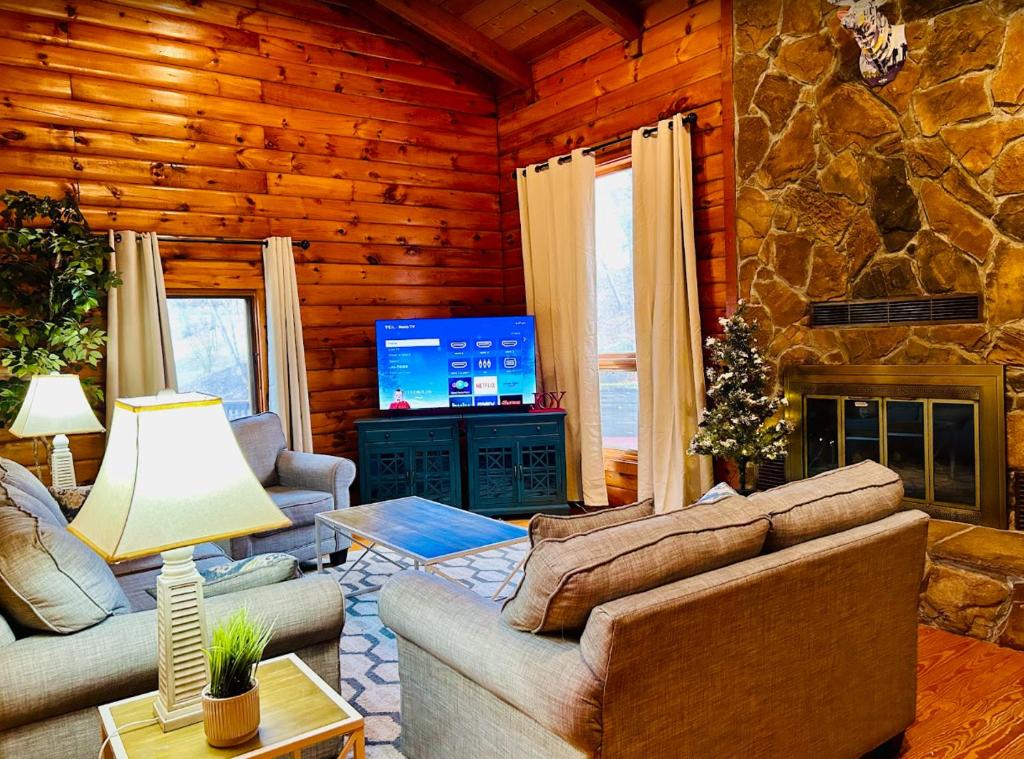una sala de estar con sofás y una chimenea en una cabaña de madera. en Cozy cabin close to Virginia Tech and Radford University, en Radford