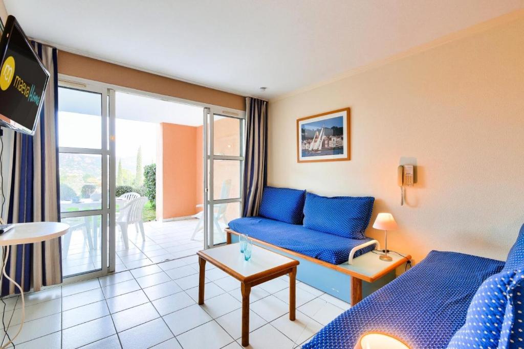 un salon avec un canapé bleu et un balcon dans l'établissement Résidence le Hameau de Cap Esterel - maeva Home - Appartement 2 Pièces 5 Personnes - Confort MAE-6795, à Saint-Raphaël