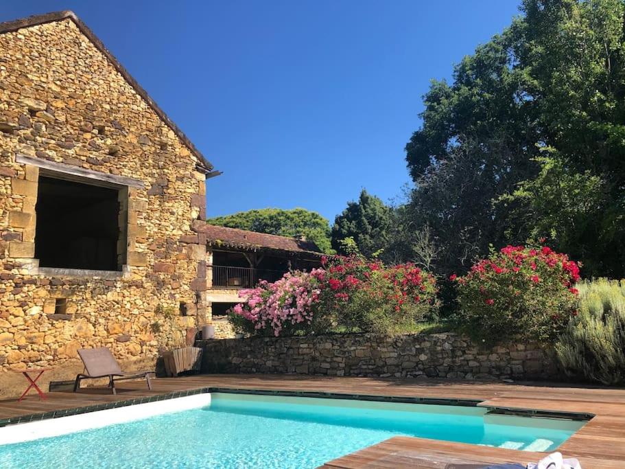 - une piscine en face d'une maison fleurie dans l'établissement Havre de paix: maison de campagne avec piscine, à Carvès