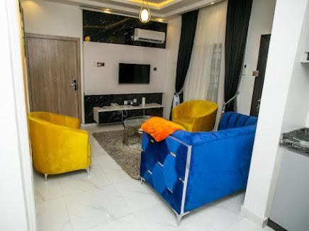 uma sala de estar com cadeiras amarelas e azuis e uma televisão em The Duch Apartments em Lagos