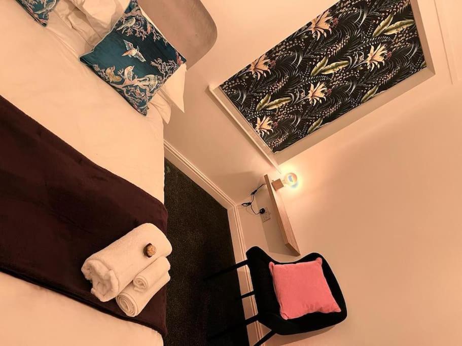a bedroom with a bed and a chair with towels at SkylinesAirbnb in Stoke on Trent