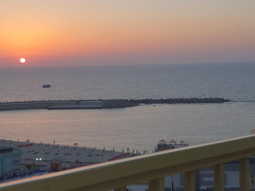 uma vista para a praia ao pôr-do-sol a partir de uma varanda em City Square شقق فندقية مكيفة باطلالة علي البحر em Alexandria