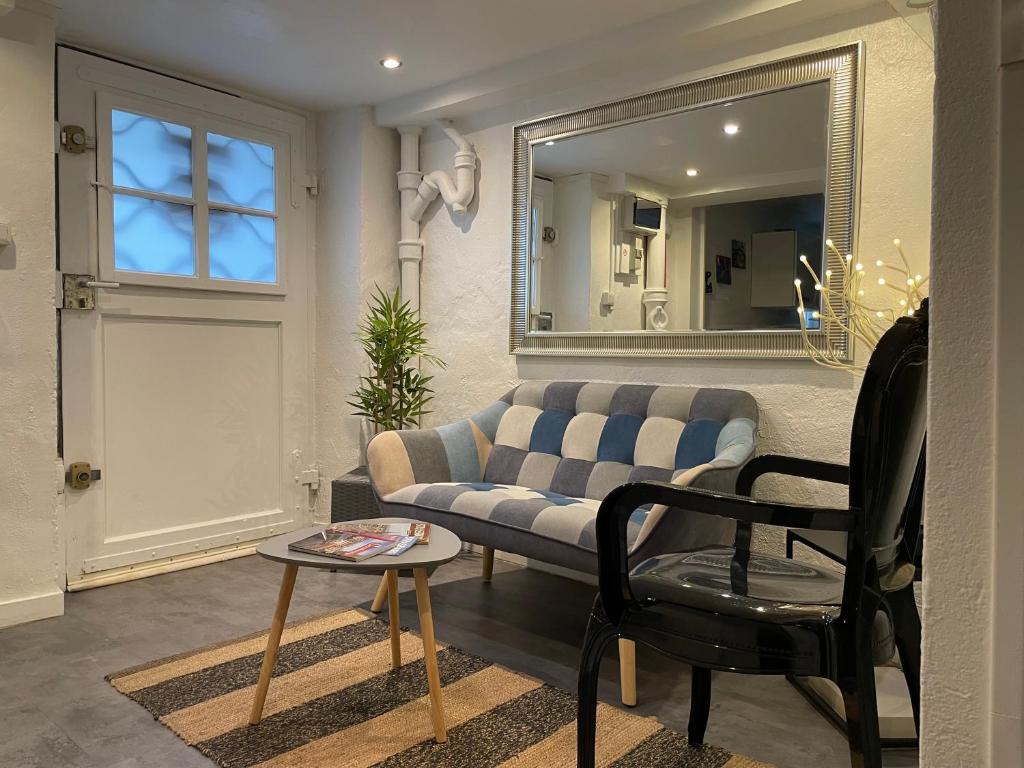 a living room with a couch and a chair and a mirror at Studio côté Parc des Contades in Strasbourg