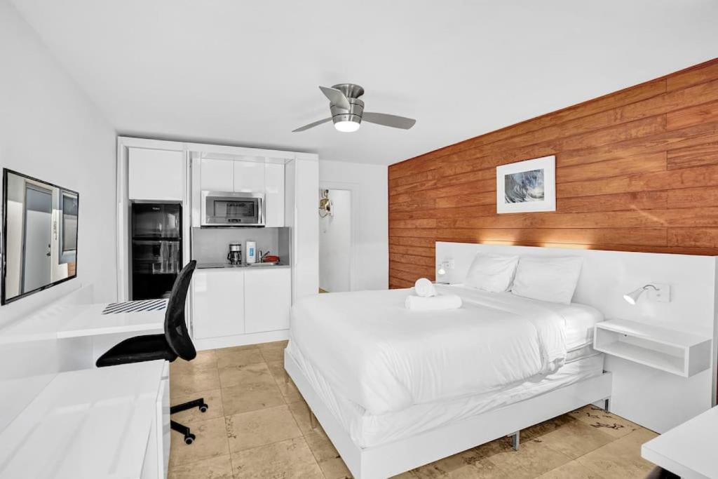1 dormitorio con cama blanca y escritorio en Waves Beach Town Studio Apartment en Pompano Beach