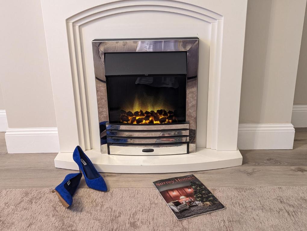a book and a fireplace in a living room with blue shoes at GREATER LONDON APARTMENT in London