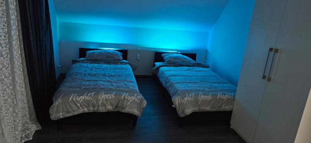 2 camas en una habitación con luz azul en Mony land en Netphen