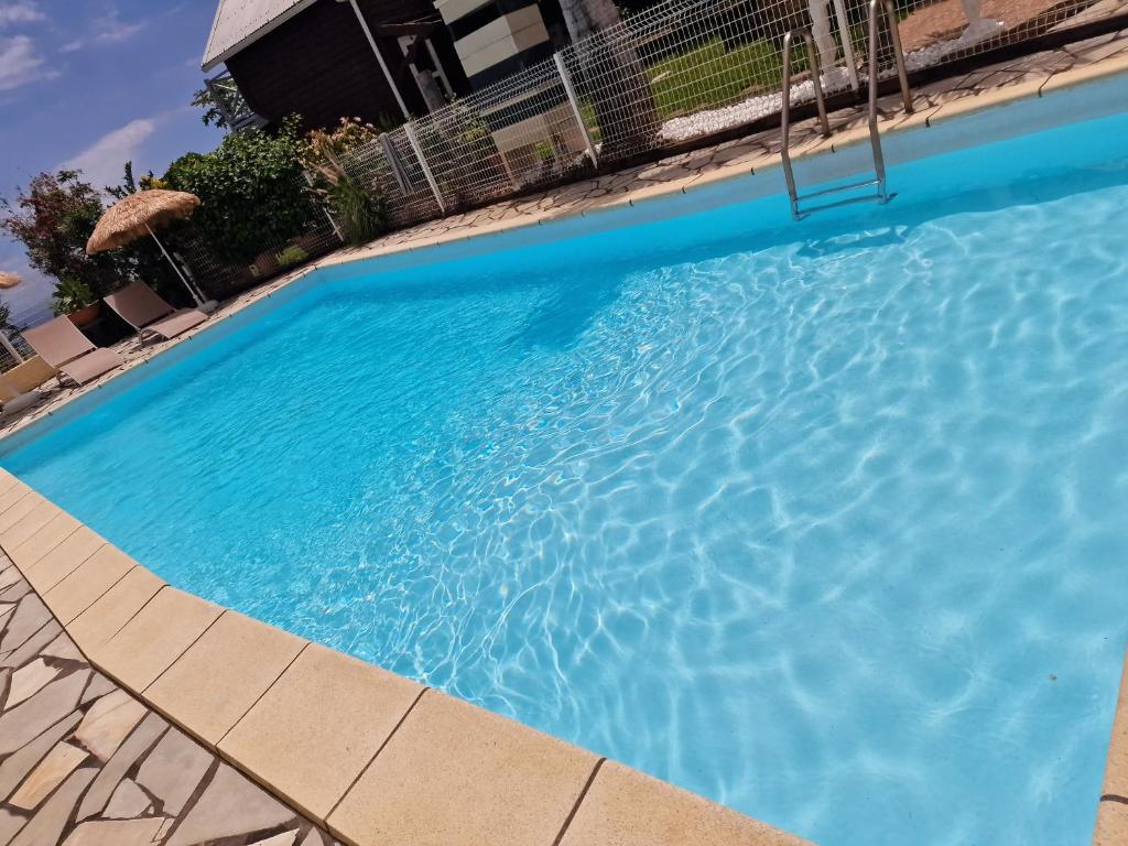 a large blue swimming pool in a yard at Lilie location sud in Petite Île