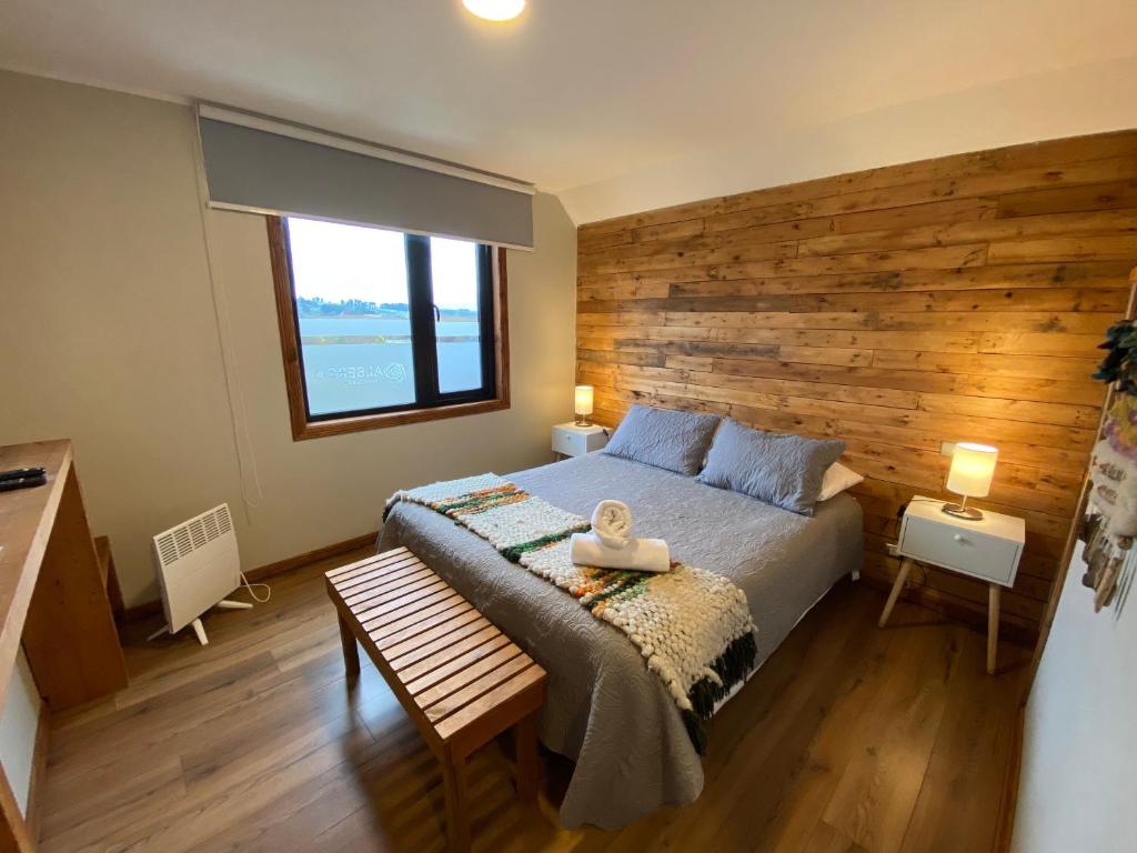 een slaapkamer met een groot bed en een houten muur bij Albergo B&B in Panguipulli