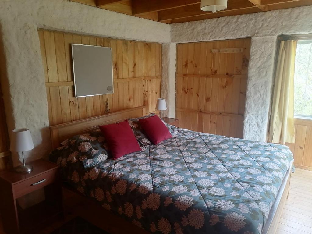 1 dormitorio con 1 cama con 2 almohadas rojas en El Refugio de la Estancia, en Isla Negra