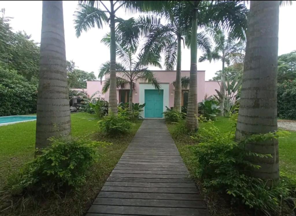 een huis met een blauwe deur tussen twee palmbomen bij Casa San Andres in Ayampe