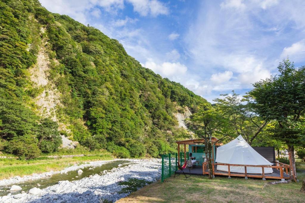 une tente à côté d'une rivière à côté d'une montagne dans l'établissement SPRINGS VILLAGE Ashigara-Tanzawa Hot Spring Resort & Glamping - Vacation STAY 42313v, à Oyama