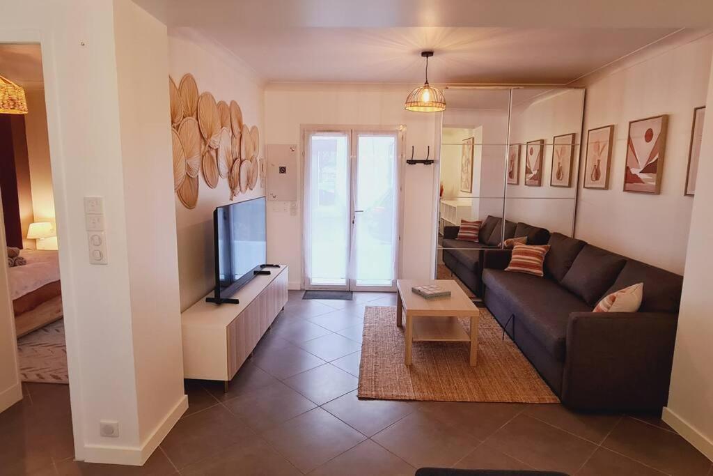uma sala de estar com um sofá e uma televisão em Appartement 2 pièces centre ville avec parking em Neauphle-le-Château