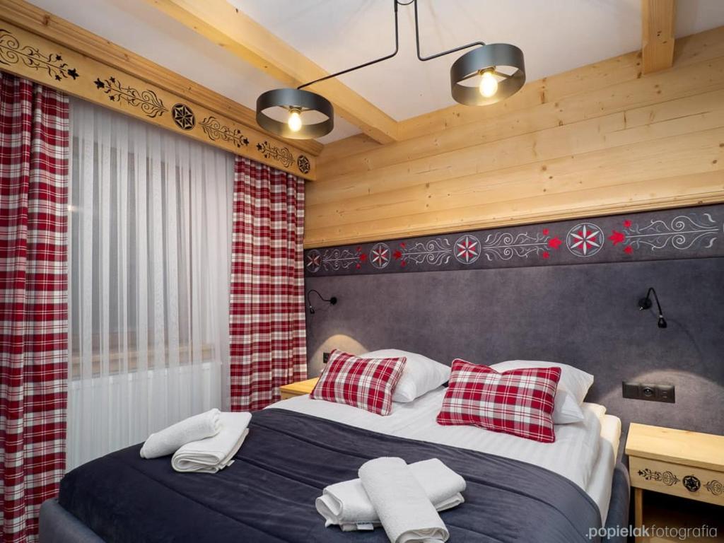 sypialnia z łóżkiem z białymi i czerwonymi poduszkami w obiekcie Apartamenty Małe Ciche w Małym Cichym