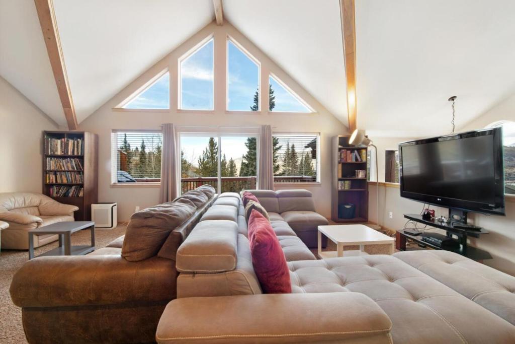 a living room with a large couch and a tv at Fawn Court - Wildernest in Silverthorne