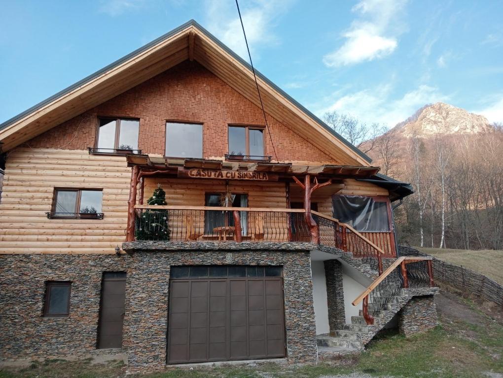 ein Blockhaus mit einem Balkon und einer Garage in der Unterkunft CASUTA CU SINDRILA in Dragoslavele