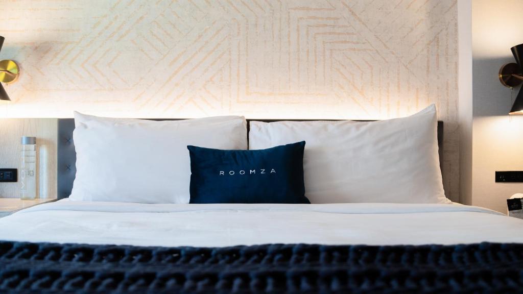 1 cama con sábanas blancas y almohadas azules en Roomza Times Square at Pestana CR7, en Nueva York