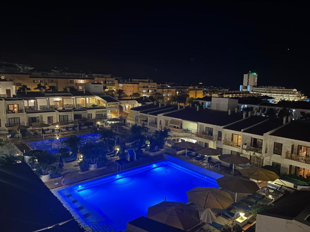 a swimming pool with blue lights in a city at night at Atlantic View Apartment Los Cristianos At Marysol Hotel Tenerife in Arona