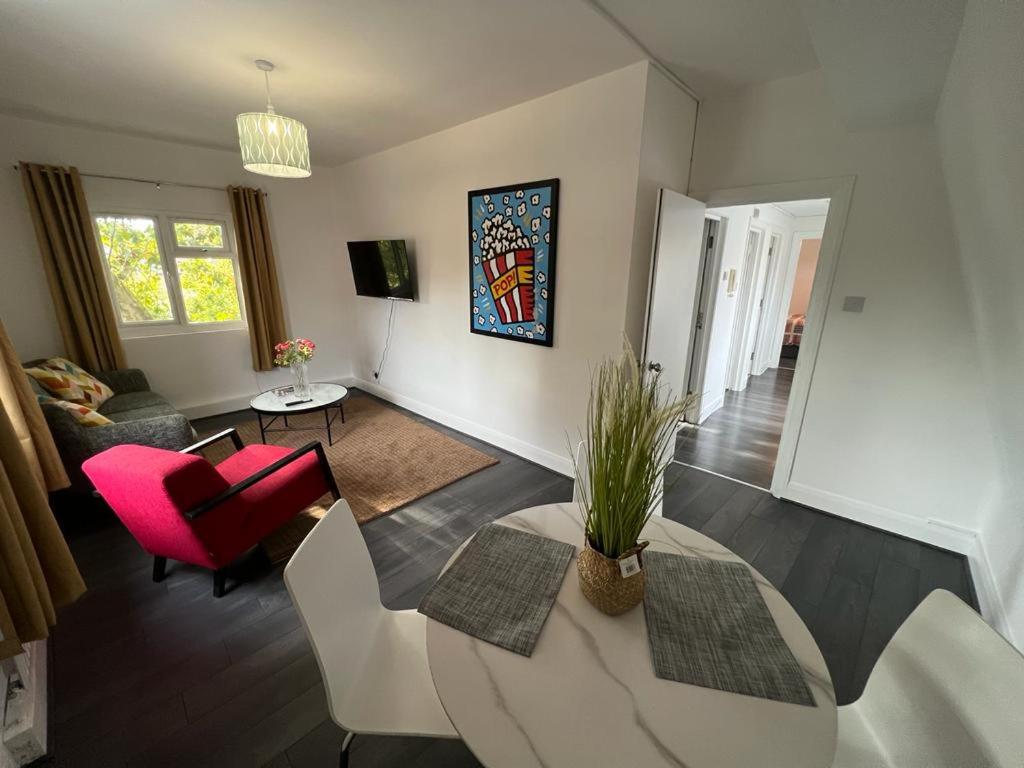 uma sala de estar com uma mesa e uma cadeira vermelha em Cozy 2 bedroom flat Tower Bridge / Bermondsey em Londres
