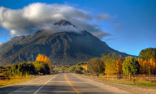 an empty road with a mountain in the background at Cabañas Mérida Hollywood in El Hoyo