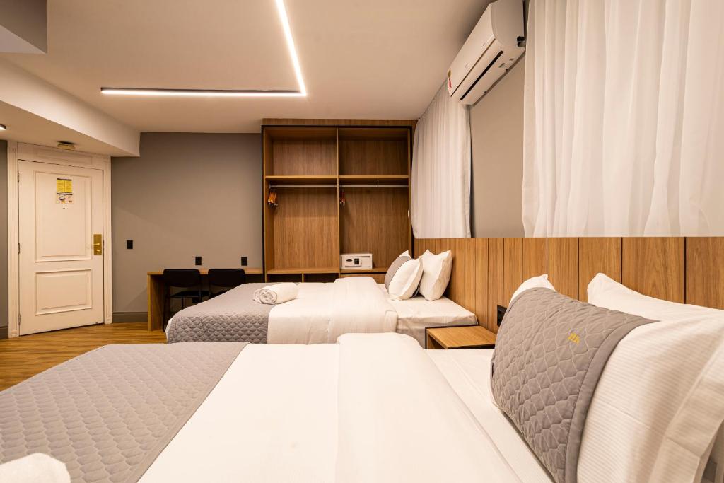 una camera d'albergo con due letti e una scrivania di You Stay at Vila Olimpia - The World a San Paolo