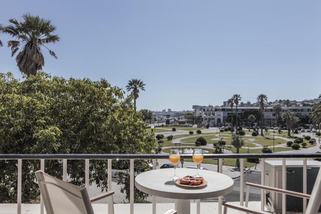 uma varanda com uma mesa e 2 copos de vinho em Rent4Rest Estoril Beachfront Apartments em Estoril